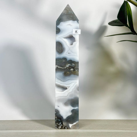 Tall, polished moss agate tower with striking white, grey, and black swirling patterns, featuring small druzy pockets.