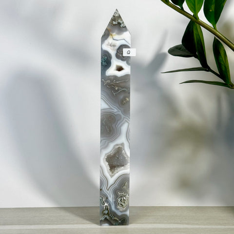 Tall, polished moss agate tower (variant Q) with white, grey, and brown swirling patterns, featuring small crystal druzy pockets.