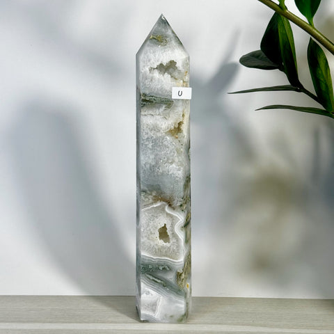 Tall, polished moss agate tower with white, gray, and green bands, featuring natural crystal geode pockets.