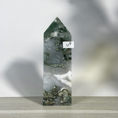 Tall moss agate tower (U2) with white, grey, and green patterns, pointed top, on a light wooden surface.