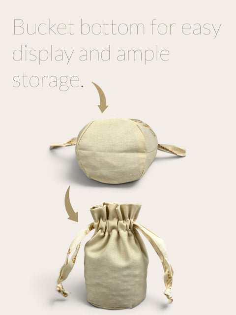 Natural cotton and linen drawstring pouch with a bucket bottom and gold embroidered ribbon for crystal storage.