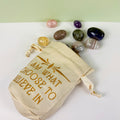Cream cotton-linen drawstring pouch with gold embroidery and assorted tumbled crystals.