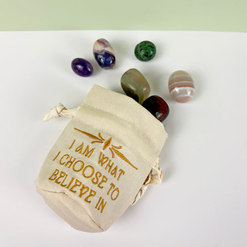 Small cream canvas drawstring pouch with gold embroidery and assorted tumbled crystals.