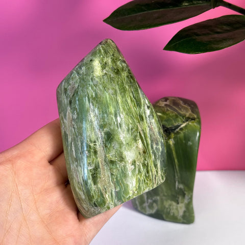 Hand holding a vibrant green Tremolite free form crystal with natural striations.