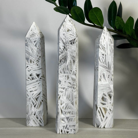 Three tall white lace agate towers with intricate geometric patterns, standing upright.
