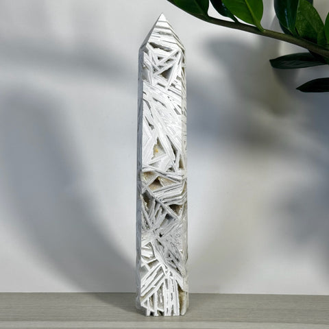 White Lace Agate Tower with intricate, angular white and gray patterns, standing tall on a wooden surface.