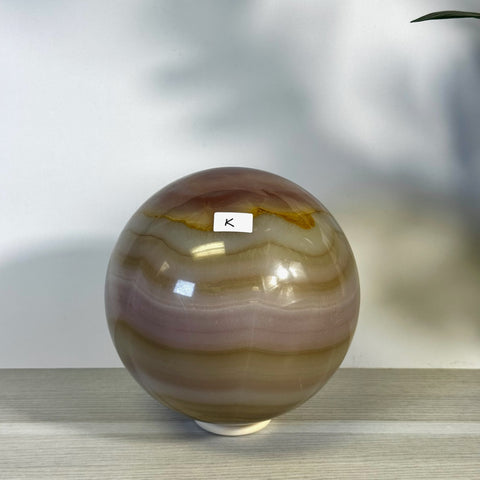 XL pink banded onyx sphere with natural brown and cream variations, marked with a white "K" label.