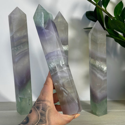 Hand holding an XL Yttrium Fluorite Tower, showing its soft lavender, lilac, and green hues.