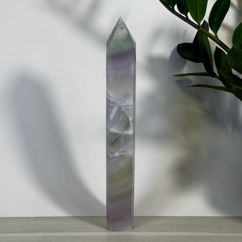 Tall XL Yttrium Fluorite Tower with purple, green, and white bands, standing on a light wood surface.