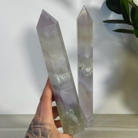 Hand holding an XL yttrium fluorite tower, showing its soft lavender to lilac hues and pointed tip.
