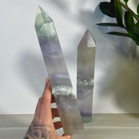 Hand holding a tall, pointed XL Yttrium Fluorite Tower with soft lavender, lilac, and green hues.