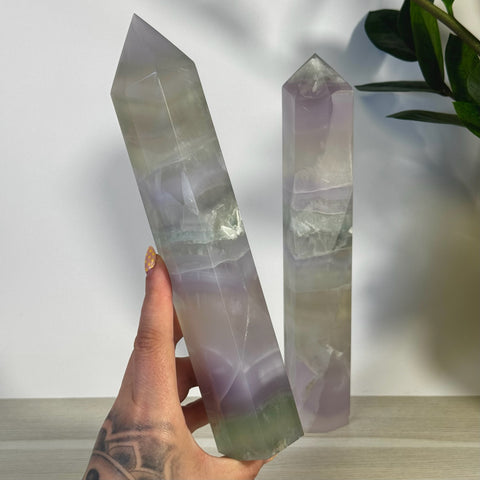 Hand holding an XL Yttrium Fluorite Tower, a tall, pointed crystal with soft lavender, lilac, and green hues.